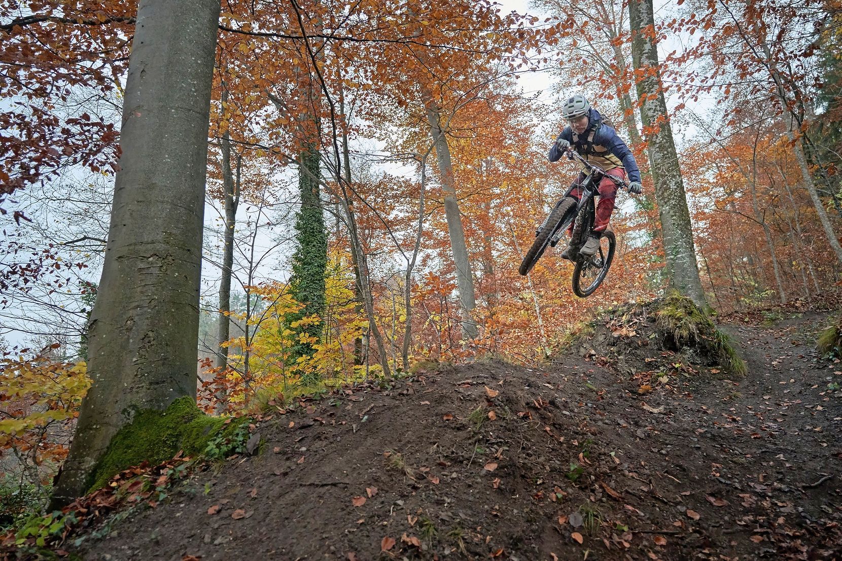 Ein Biker macht einen Sprung über einen Hügel.